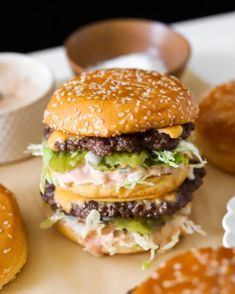 Stacked homemade Big Mac with sesame buns, two beef patties, cheese, pickles, shredded lettuce and pink sauce